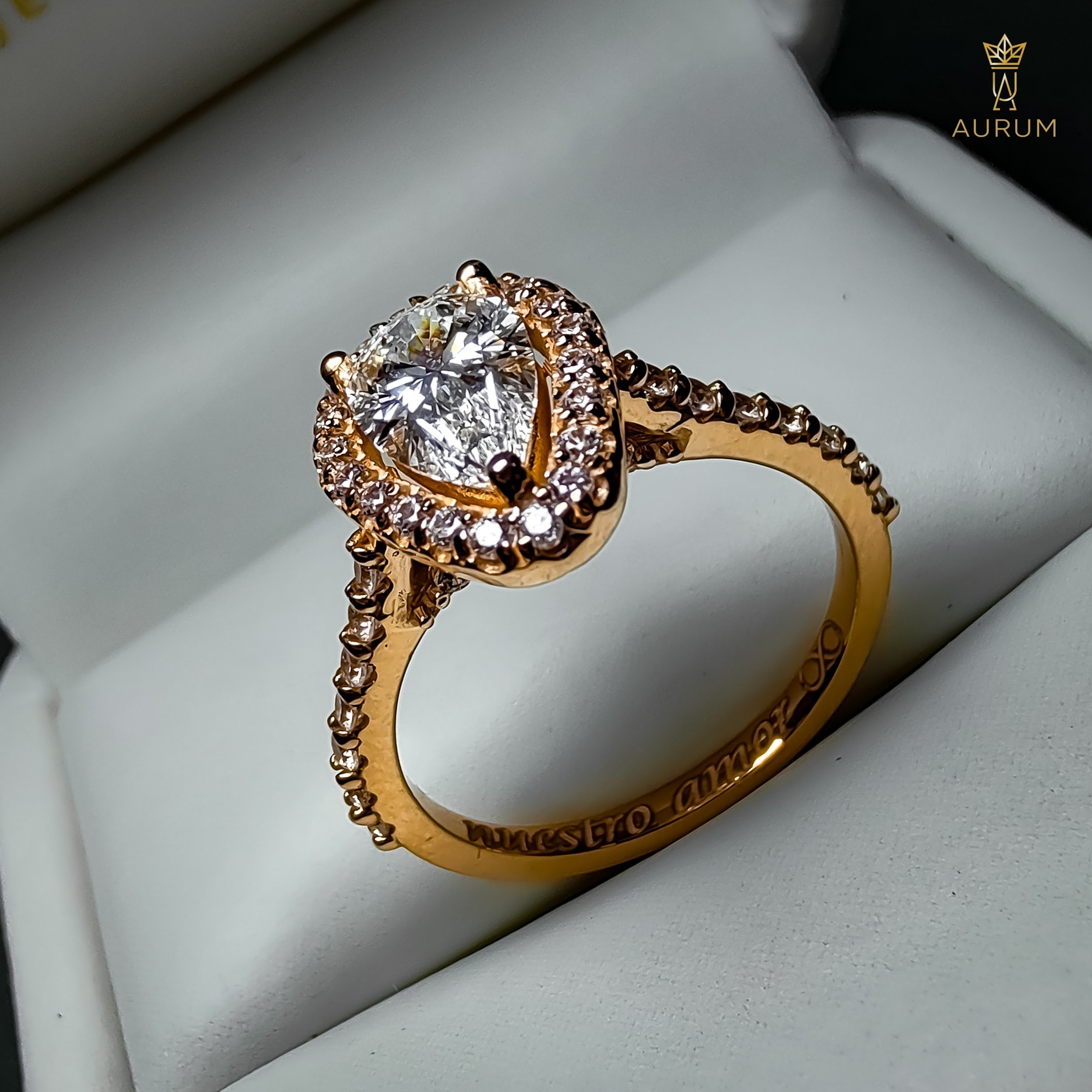 Perfil de anillo de compromiso con diamante en forma de pera, halo y banda pavé en oro rosa, con grabado interior visible
